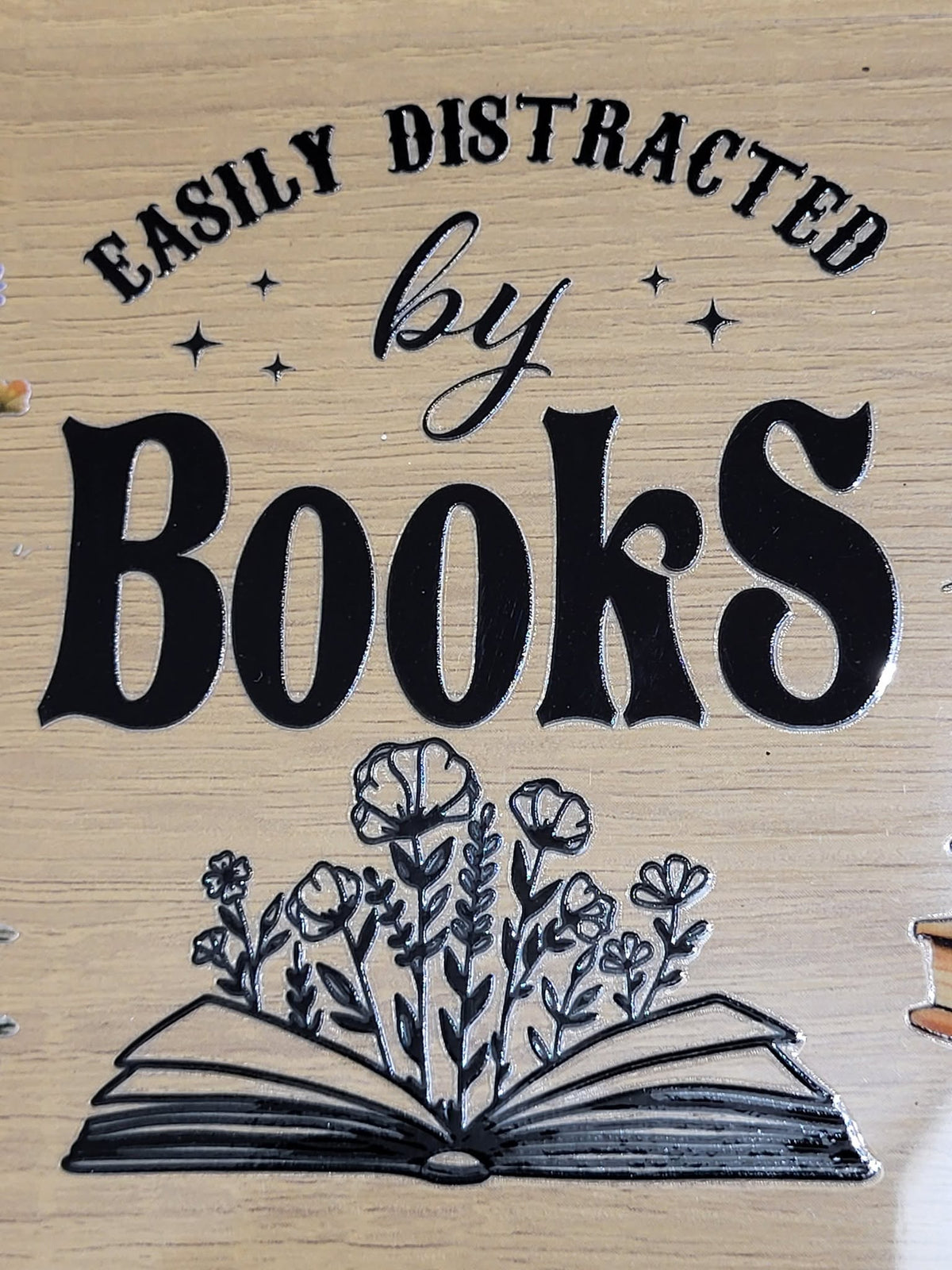 Easily Distracted by Books - bold black and white design with arched text over an open book blooming with wildflowers and sparkle stars