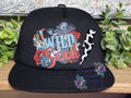 Wild Soul Trucker Hat in Black with boho western graphic and cow print lightning bolt patch